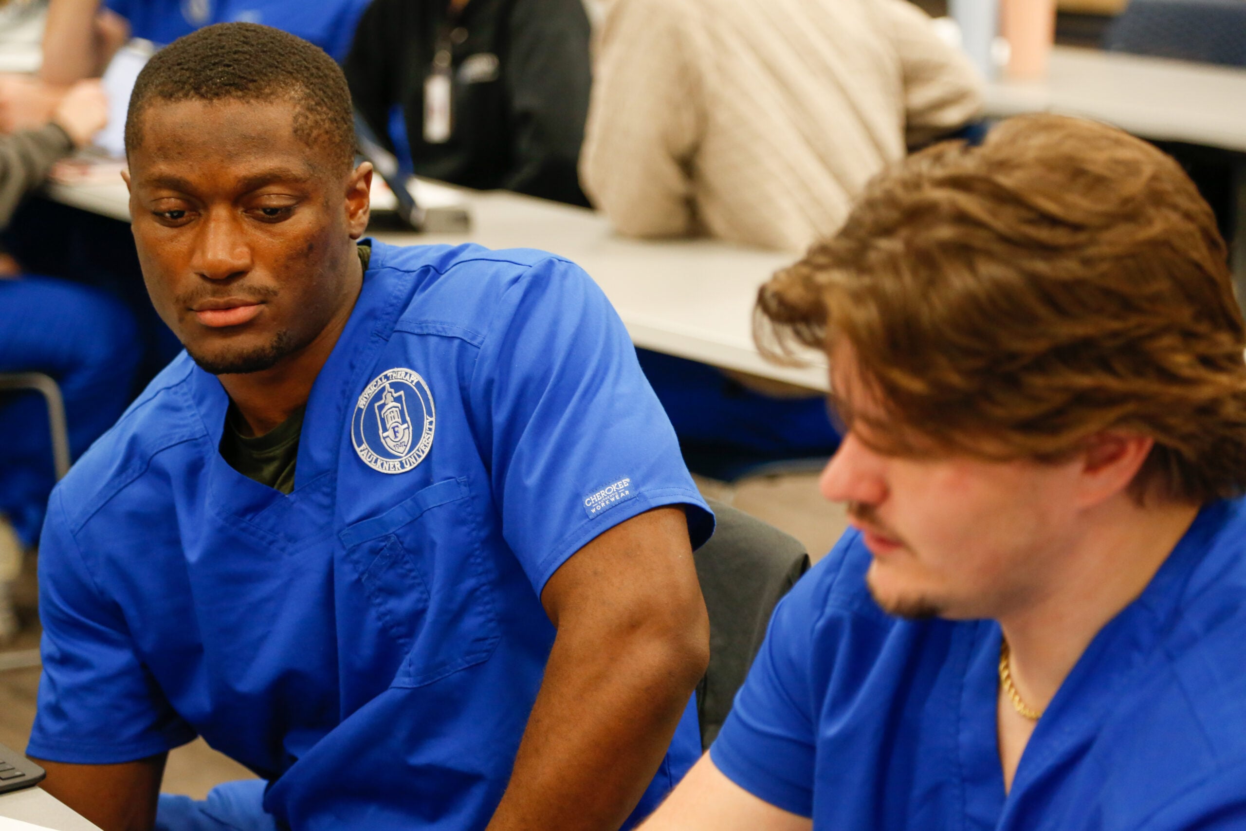 Two male PT students reviewing material at desk